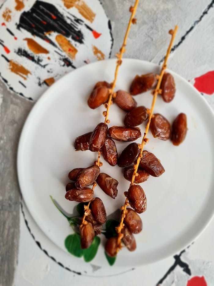 Home Two sprigs of fresh dates beautifully arranged on a plate, perfect for Ramadan iftar.