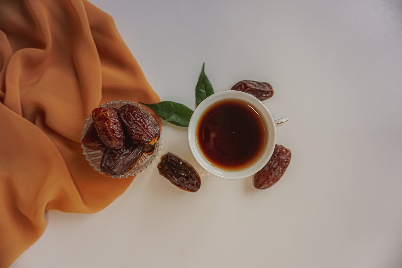 Home Top view of a cup of tea surrounded by dried dates and a cloth on a white counter.