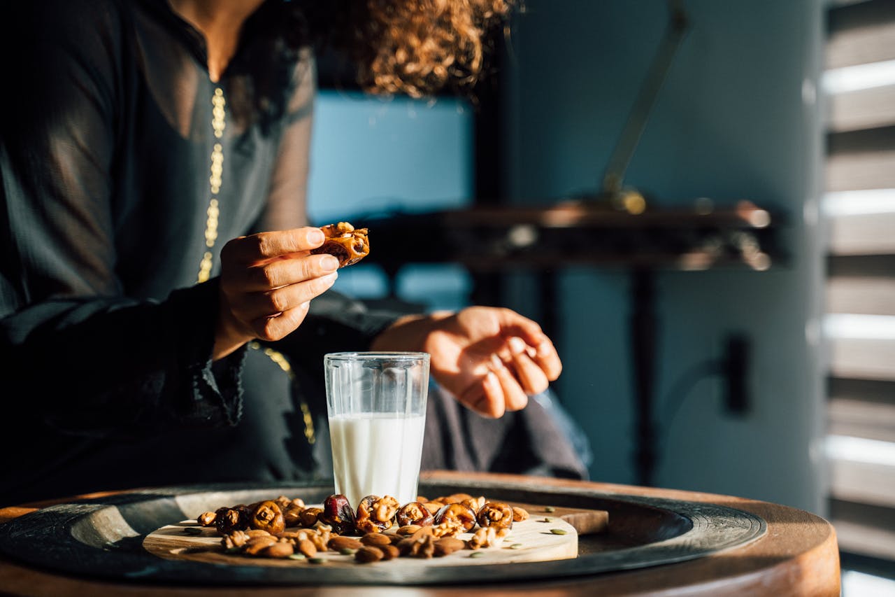 Home A woman enjoying dates and a glass of milk with sunlight streaming in indoors.